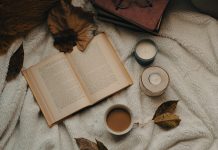 ein Buch liegt aufgeschlagen zwischen Laubblättern und Kerzen